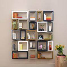 a book shelf with many books on it and a vase full of flowers next to it