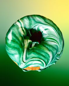 a donut with green and white swirled icing on it's side in the air