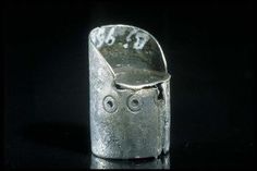 a metal object that looks like it has eyes and is sitting on a black surface