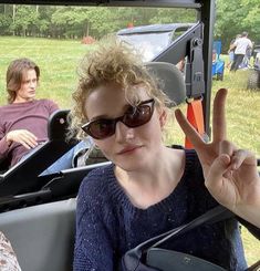 two people sitting in a golf cart making the peace sign with their hands while another person stands behind them