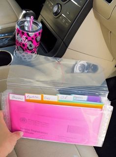 a person holding a pink folder in their car