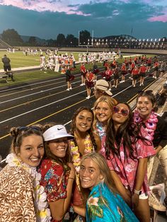 a group of young women standing next to each other in front of a football field