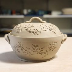 a white casserole sitting on top of a counter next to a bowl with handles