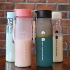 three different types of water bottles sitting on a wooden table next to a brick wall