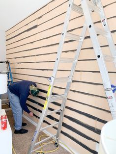 a man working on a wall with ladders