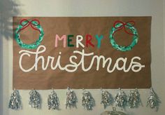 a merry christmas sign hanging on the wall next to a bell and wreath with bells