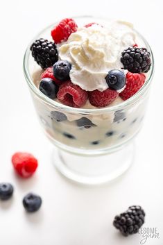 berries, whipped cream and raspberries in a glass bowl on a white surface