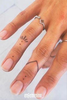 a woman's hand with tattoos on it and a ring in the shape of a sun