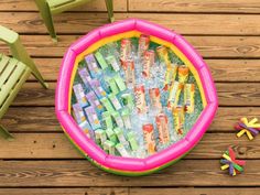 an inflatable tub filled with candy sitting on top of a wooden floor next to chairs