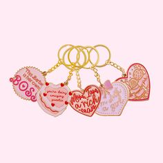 six heart shaped key chains with different sayings on them, all in gold and pink