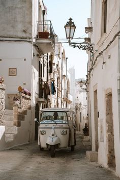 an old car parked on the side of a street next to a building with balconies