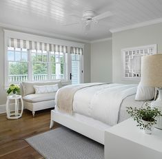 a bedroom with a bed, chair and window in the room that has white shutters