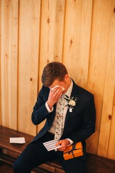 a man in a suit and tie sitting on a bench holding his hand to his face