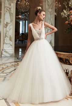 a woman in a white wedding dress standing on a marble floor with chandelier