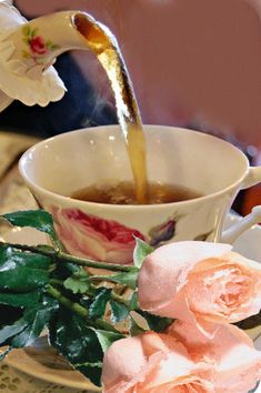 tea being poured into a cup with pink roses