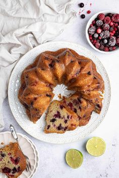 a bundt cake on a plate with raspberries and limes next to it