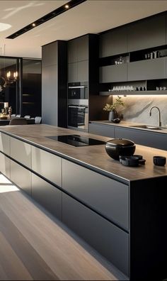 a modern kitchen with an island counter and black cabinets in the center is lit by pendant lights