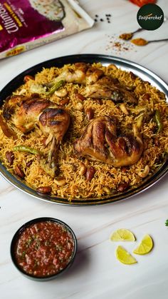 a plate full of chicken and rice next to some dipping sauces on the side