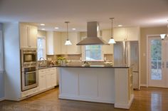 an empty kitchen with white cabinets and stainless steel appliances in the middle of the room