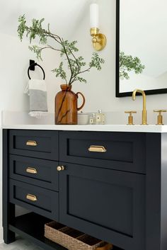 a bathroom vanity with black cabinets and gold handles