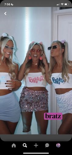 three beautiful women standing next to each other in front of a mirror wearing matching outfits