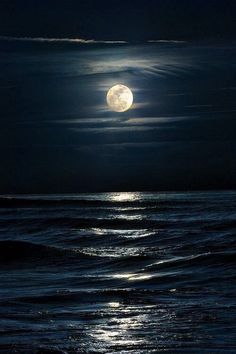 the full moon is shining over the ocean and waves in the water at night time