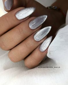 a woman's hand with white and silver nail polishes on her nails,