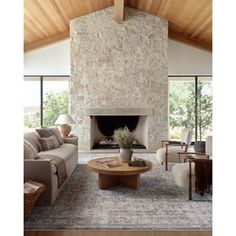 a living room filled with furniture and a fire place in front of a stone wall