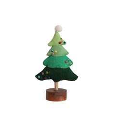 a small green christmas tree sitting on top of a wooden stand