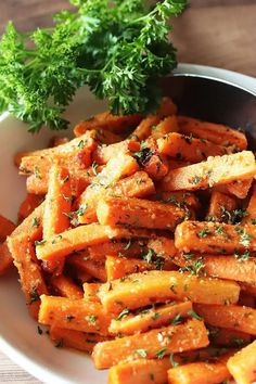 a white plate topped with cooked carrots and parsley