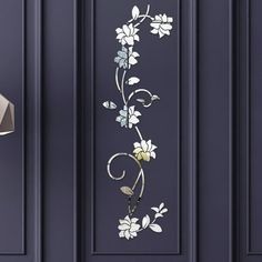 a blue door with white flowers and leaves painted on the side by an iron lamp