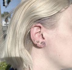 a woman with blonde hair wearing a pair of ear piercings on her left side