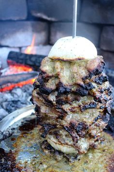 a stack of food sitting on top of a pan over an open fire pit,