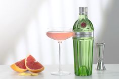 a bottle of gin next to a wine glass and grapefruit