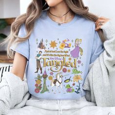 a woman wearing a blue tshirt with the words tangled on it, surrounded by cartoon characters