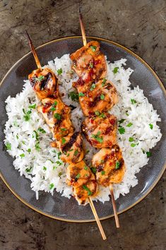 chicken skewers with white rice on a plate