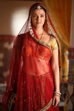 a woman wearing a red and gold bridal outfit