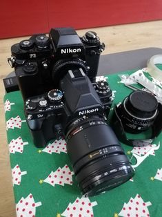 two cameras sitting on top of a green table cloth