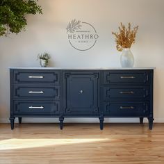 a blue dresser with two vases on top of it and the logo heathro home