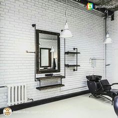 a white brick wall in a salon with black chairs and mirrors on the wall,