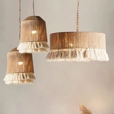 two chandeliers hanging from chains with white ruffled lampshades on them