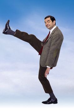 a man in a suit and tie kicking a soccer ball with his feet on the ground