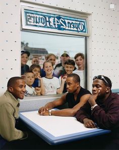 three young men sitting at a table in front of a sign that says open 24 hour