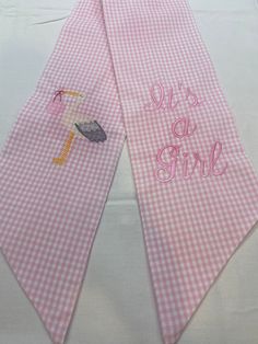 two pink gingham cloths with an umbrella and the words it's a girl on them