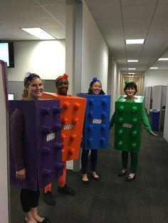 four people dressed in lego costumes standing next to each other on the hallway between an office building