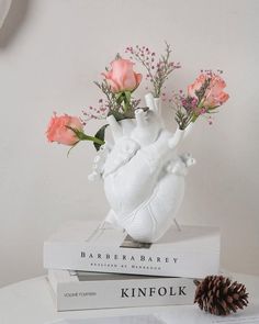 a white vase with flowers on top of two books