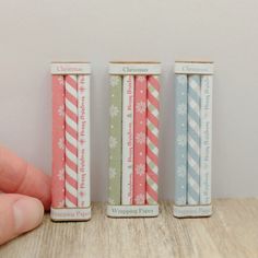 three small candles sitting on top of a wooden table next to each other in different colors