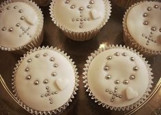 six cupcakes with white frosting and pearls on them are arranged in a circle