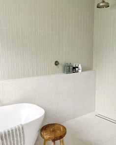 a white bath tub sitting next to a wooden stool