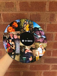 a hand holding up a circular photo collage on a brick wall